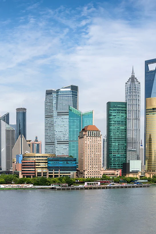Shanghai Panoramic view of Shanghais skyline featuring the Oriental Pearl Tower and various skyscrapers along the waterfront, under a clear blue sky. The Huangpu River is in the foreground with boats visible on the water. (This text has been generated by AI)