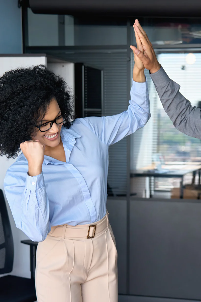 Cheerful successful coworkers colleagues indian businessman and African American businesswoman giving high five celebrating project victory in modern office. Business corporate culture concept.