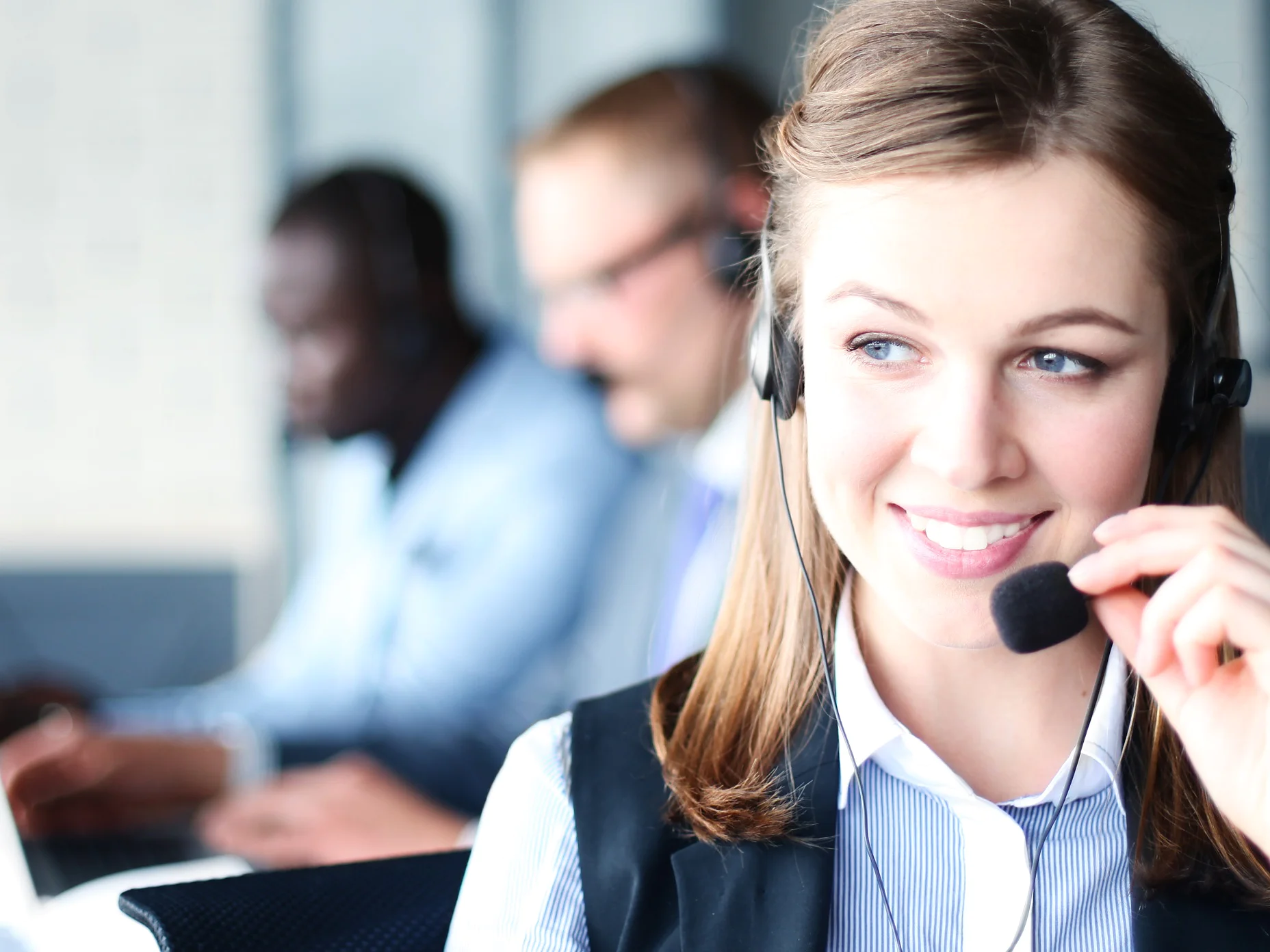 Portrait of call center worker accompanied by her team. Smiling customer support operator at work.