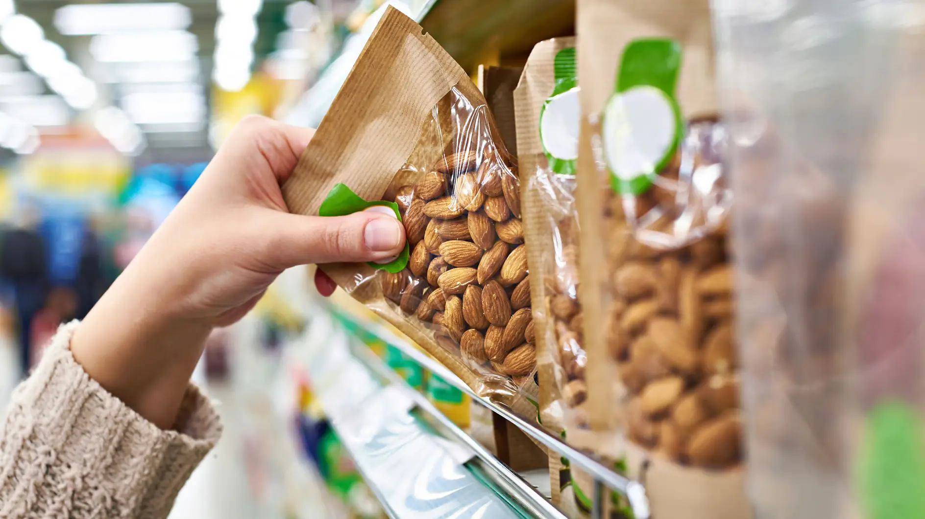 Hand with packaging of almond nuts in store