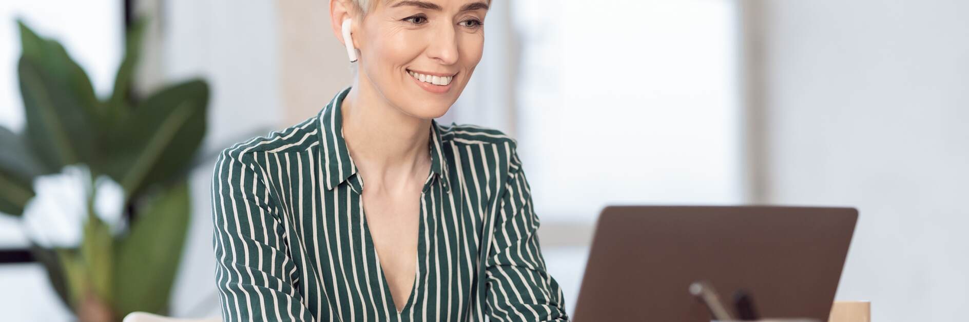 Femme mûre travaillant sur un ordinateur portable avec des écouteurs, assise au bureau