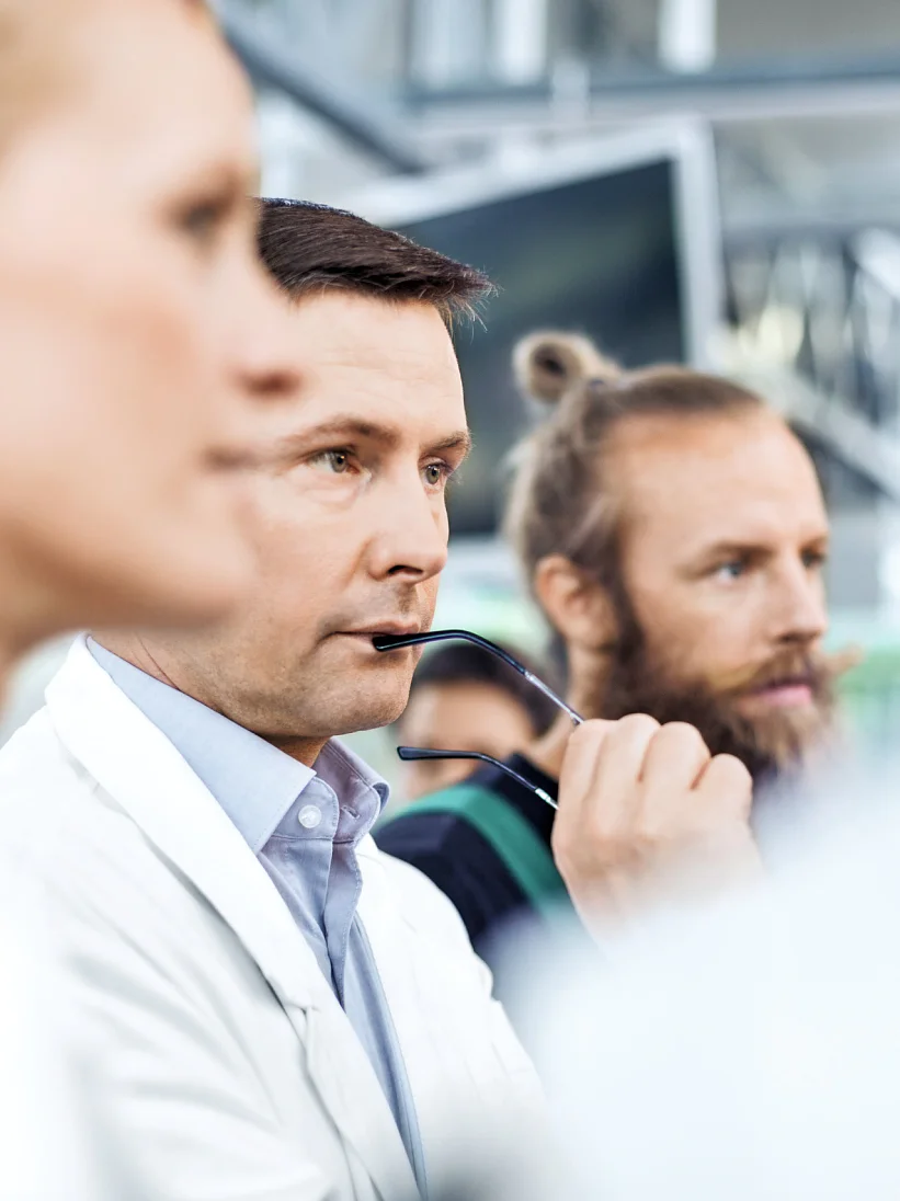 Thoughtful male scientist with farm workers standing in greenhouse