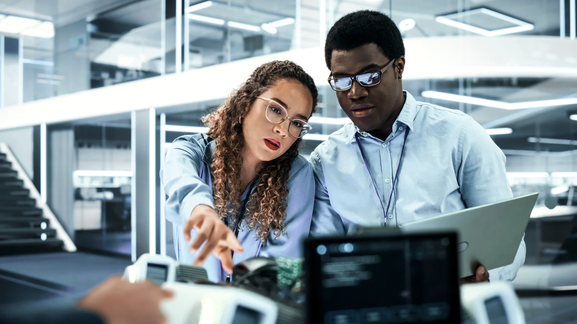 Portret van twee multiculturele industriële robotica-ingenieurs die een laptop gebruiken om aan een robothond te werken. Collega's die de interface opzetten voor een mobiel AI-robotconcept.