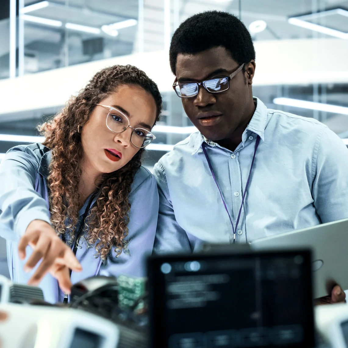 Portret van twee multiculturele industriële robotica-ingenieurs die een laptop gebruiken om aan een robothond te werken. Collega's die de interface opzetten voor een mobiel AI-robotconcept.