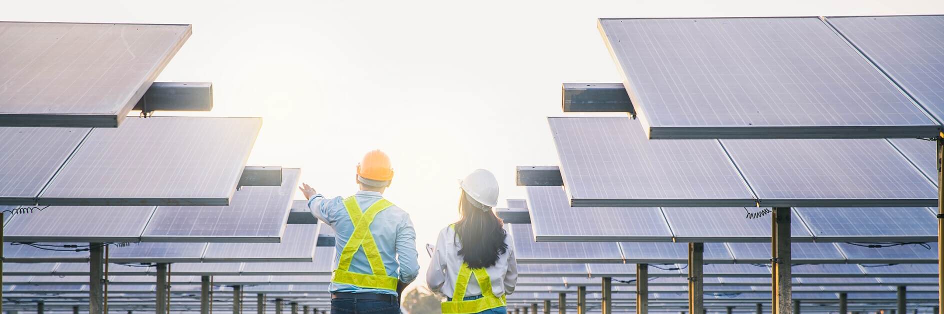 Erkek ve kadın çalışan bakım panelleri güneş enerjisi toplarken. Güneş enerjisi endüstrisinde kontrol ve bakım ekipmanları üzerinde çalışan mühendis.
